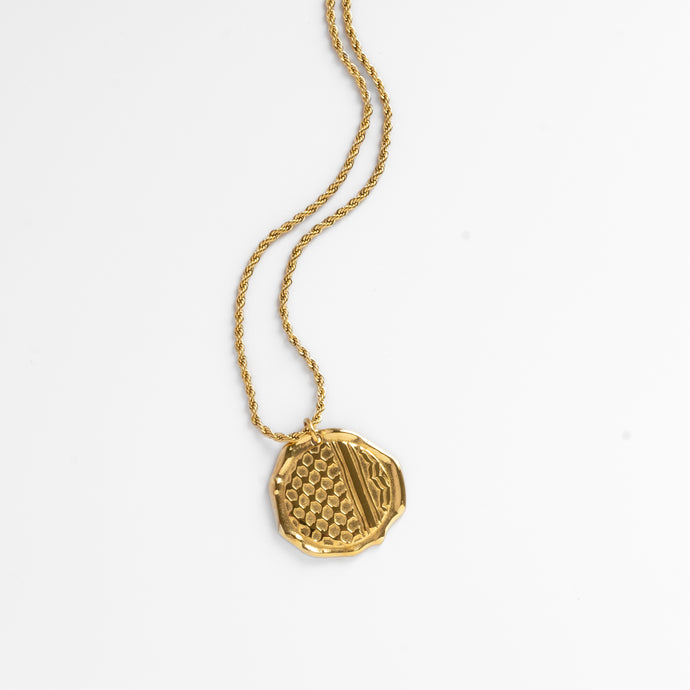 Gold kuffiyeh/keffiyeh necklace with a textured pendant on a white background